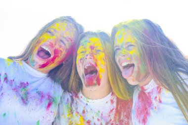 Teenager friends with dry colors. Drycolors. Teenage school friends having fun piggybacking outdoors with dry colors. Happy mood with colorful drycolors. Colorful holi on painted face. clipart