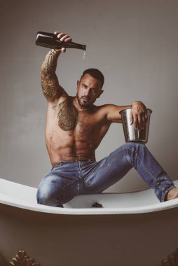 Lüks elit eğlence. Lüks hayatı şampanya şişesi ile kavramı. Acımasız adam, banyo içine dökülen şampanya ile. Lüks hayat. Lüks elit alkol ile çekici erkek.