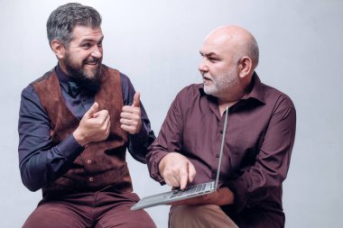 Yaş eğitim. E-öğrenme: oğlum ve kıdemli babası. Bir dizüstü bilgisayar kullanımını açıklar. Nesiller. Gülümseyen kıdemli bayım ve okuldan eve genç erkekler. Farklı yaş nesillerin aile.