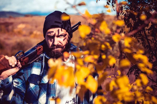 Bearded hunter huntering. Hunting period, autumn season. Hunter with a hunting gun and hunting form to hunt in forest. Hunter man.