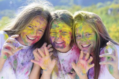Teenager friends with dry colors. Drycolors. Teenage school friends having fun piggybacking outdoors with dry colors. Happy mood with colorful drycolors. Colorful holi on painted face. clipart