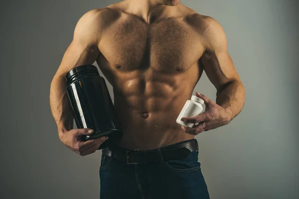 Une routine diététique. Stimuler la croissance musculaire avec des stéroïdes anabolisants. Hormone anabolique augmente la force musculaire. Un homme fort tient des bouteilles de vitamines. Homme avec six abdos pack. Nutrition vitaminique. Une alimentation saine — Photo