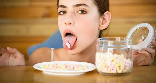 Sweet tooth. Candy girl with sweet confectionery. Pretty woman hold marshmallows on tongue. Funny woman enjoy eating marshmallows. Junk food. Unhealthy and harmful food. Sweet snack