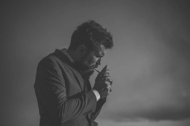 Adam sakal ve arka plan üzerinde dramatik gökyüzü ile sigara.