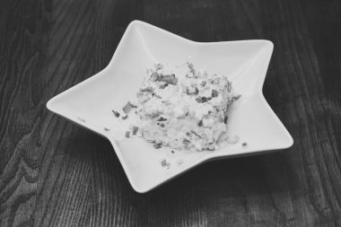 Yıldız şeklinde beyaz plaka Olivie salata servis. Geleneksel yemeği restoranda - Olivie salata, ahşap arka plan. Restoran yemek kavramı. Yeşil soğan ile dekore edilmiş salata