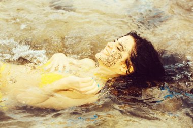 Oldukça mutlu kız denizde yatan seksi sarı mayo