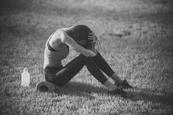 Sportovkyně sedět na zelené trávě s náčiním na léto — Stock fotografie