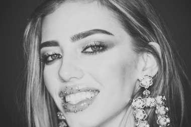 Makyaj kavramı. Şehvetli dudakları ile kadın çekici görünüyor. Güzellik moda kız makyaj ile içinde yapay elmas, göz farı, maskara, rujla giyer köpüklü büyük küpeler takı, koyu arka plan.