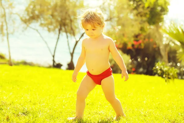 Schattige babyjongen loopt op groen gras — Stockfoto