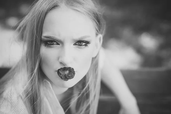 Vackra professionell modell att hålla röd blomma i munnen. Vackra damen tittar direkt på kamera. — Stockfoto