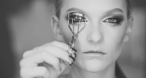 Look, woman use eyelash curler for eye makeup. Look of beauty woman with curly long eyelashes