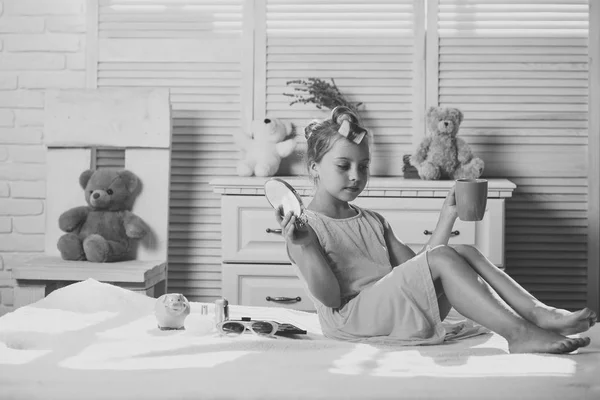 Dítě sedí na posteli s růžovou cup a zrcadlo — Stock fotografie