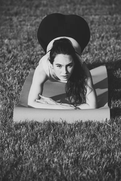 Fitness woman with ponytail doing plank position on green grass