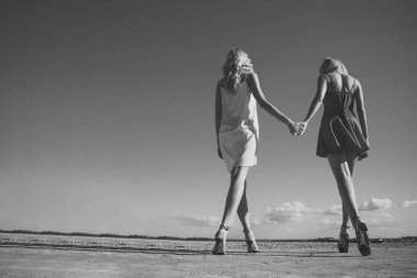 İkizler yaz aylarında mavi gökyüzü arka plan üzerinde yürümek.