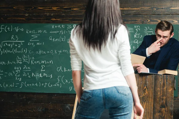 Ensinar é a minha paixão. Educação em escolas universitárias ou domiciliares. Um homem esperto conserta óculos no nariz. Professor olhar para estudante mulher em jeans visão traseira. De volta à escola. Actividades de ensino e aprendizagem — Fotografia de Stock