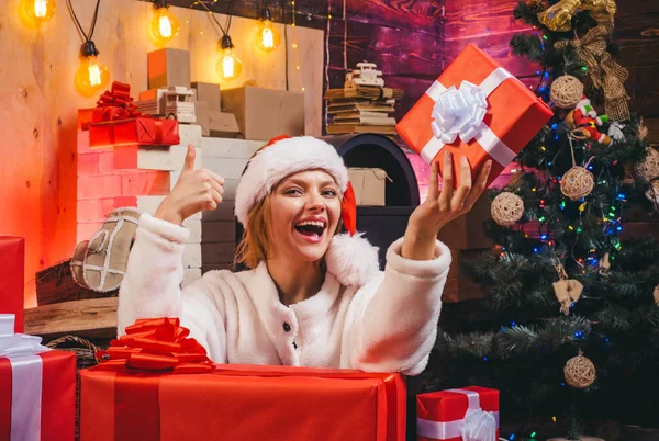 Leende kvinna dekorera julgran hemma. Öppen mun. Glad jul. Lycklig kvinna. Juldekorationer och presentförpackning på trä bakgrund. Christmas klänningar. — Stockfoto