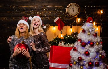 Kırmızı Santa şapka mevcut tutan kız. Arkadaş Noel. Noel ve yeni yıl kavramı. Şehvetli kadın. Noel ağacı ile kapalı modeli iki kız moda portre.
