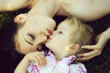 Gülümseyen sevimli çocuk ve güzel anne yeşil çim üzerinde yalan