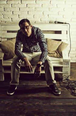 adam gözlük ve mikrofon ile bankta kareli gömlek