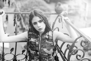 Kamuflaj yeleği metalik balkon raylar tutan güzel kız