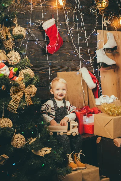 Glückliche kleine Kinder mit Weihnachtsmütze und Geschenk haben ein Weihnachtsfest. niedliches kleines Mädchen schmückt den Weihnachtsbaum drinnen. Geschenke zu Weihnachten und Neujahr. — Stockfoto