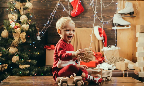 Fröhliches süßes Kind, das ein Weihnachtsgeschenk öffnet. kiddy. Kinder haben Spaß in der Nähe des Weihnachtsbaums drinnen. Neujahrskinder. Winterkinder. Kindergeschenk. — Stockfoto