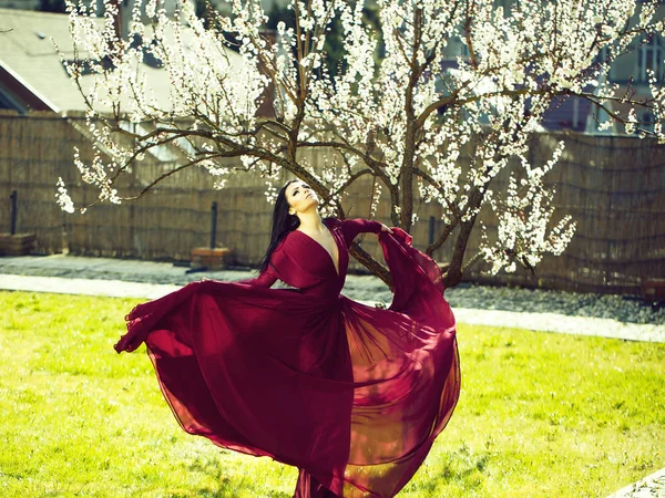 Yakınındaki çiçeği Kırmızı elbiseli kız — Stok fotoğraf