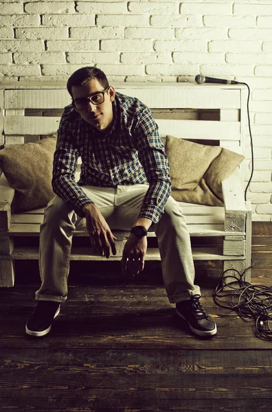 adam gözlük ve mikrofon ile bankta kareli gömlek