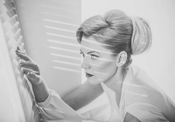 Žena s koncentrovanou obličej s make-upem vypadá přes žaluzie, špionáž. — Stock fotografie