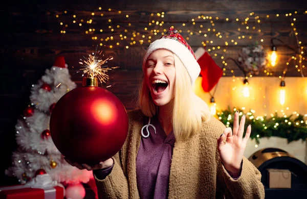 Mulher de Natal segura bomba. Mulher sorri de Natal. Feliz Natal e Feliz Ano Novo. Cara cómica maluca. Uma jovem piscadela. Arrepios de banda desenhada . — Fotografia de Stock