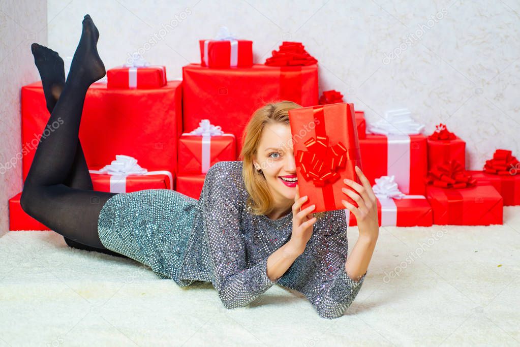 Glamour celebration. Christmas fashion. Smiling beautiful young girl holding red present box. Sexy Santa Clause woman in elegant dress. Sexy woman. New year girl. Sensual young girl.