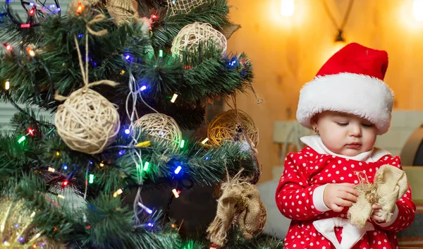 Забавный ребенок с рождественским подарком. Рождественские дети. Милый малыш украшает рождественскую елку в помещении. Счастливые младенцы с подарком . — стоковое фото