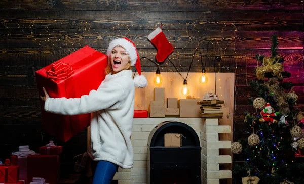 Glamour kutlama yeni yıl. Sarışın Noel Baba hediye kutusu, duvar tutan kadın. Noel giysileri giyen güzel kız portresi. Kırmızı Santa şapka mevcut tutan kadın. Kadın Noel. — Stok fotoğraf