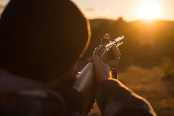 Hunter with shotgun gun on hunt. Hunter with Powerful Rifle with Scope Spotting Animals. Close up snipers carbine at the outdoor hunting.