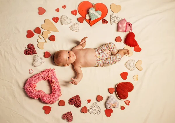 Kärlek. Barndomen lycka. Alla hjärtans dag. Liten flicka bland röda hjärtan. Söta lilla bebis. Nytt liv och födelse. Familj. Barnomsorg. Kärlek och tillit. Porträtt av glada lilla barnet — Stockfoto