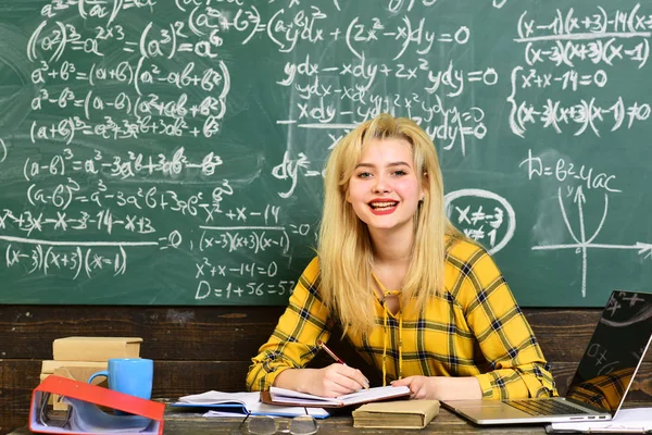 Estudiantes atentos escriben algo en sus bloc de notas mientras están sentados en escritorios en el aula. Estudiantes que se comunican durante el recreo entre conferencias en un auditorio . — Foto de Stock