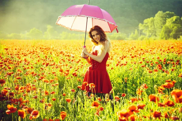 赤いケシ畑でピンクの傘を持つ幸せな女の子 — ストック写真