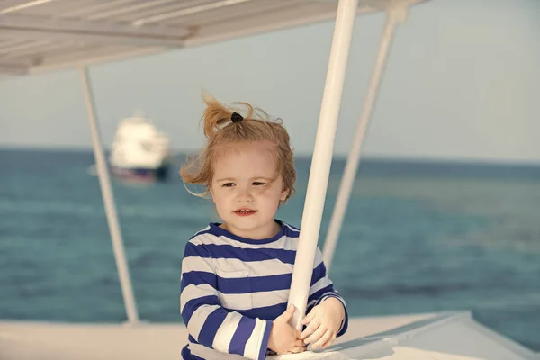 Enfant en chemise rayée regardant l'eau de mer bleue — Photo