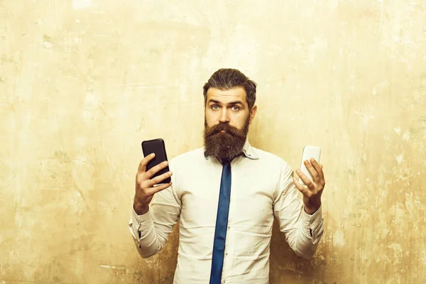Parrakas mies tai hipster vertailla matkapuhelin ja älypuhelin — kuvapankkivalokuva