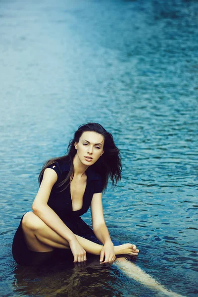 Joven sexy mujer sentado en el agua — Foto de Stock