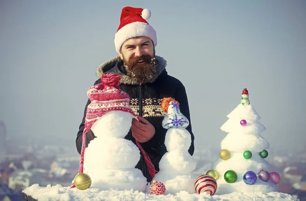 Щасливий Санта чоловік кладе капелюх на сніговика — стокове фото