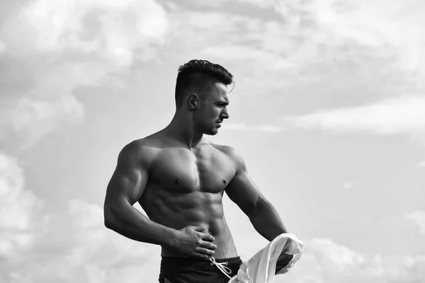 Sexy muscular hombre desvestirse en cielo fondo — Foto de Stock