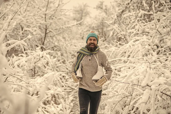 Homem feliz barbudo segurar patins na floresta de inverno nevado, natal — Fotografia de Stock