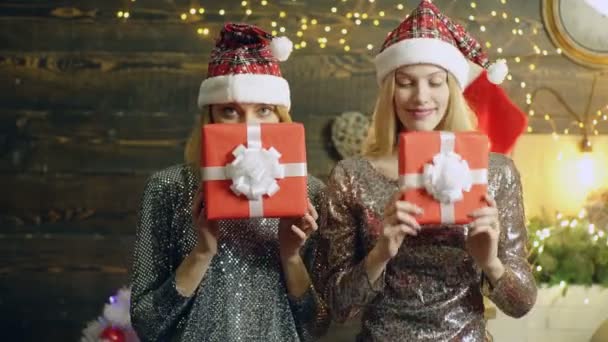 ギフトの存在の背後にある自分の顔を隠す新しい年帽子のブロンドの女の子 赤い帽子の女の子は 新しい年の背景にクリスマス プレゼントを紹介します 正月気分のコンセプト — ストック動画