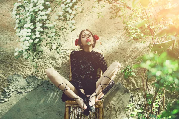 Hübsches Mädchen bindet an sonnigem Tag Schnürsenkel auf Weidenstuhl — Stockfoto