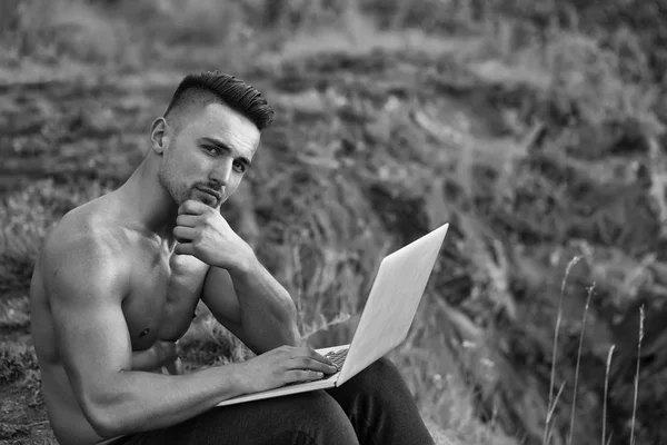Zamyślony muskularny mężczyzna z laptopa odkryty — Zdjęcie stockowe