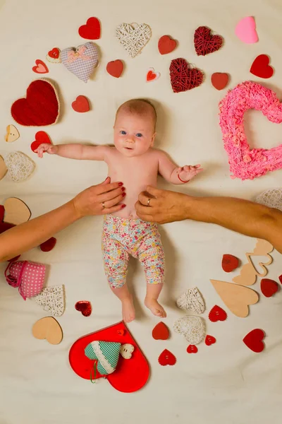 Love and trust. Becoming a family. Childhood happiness.Valentines day. Love. Portrait of happy little child. Small girl among red hearts. Sweet little baby. New life and birth. Family. Child care — Stock Photo, Image