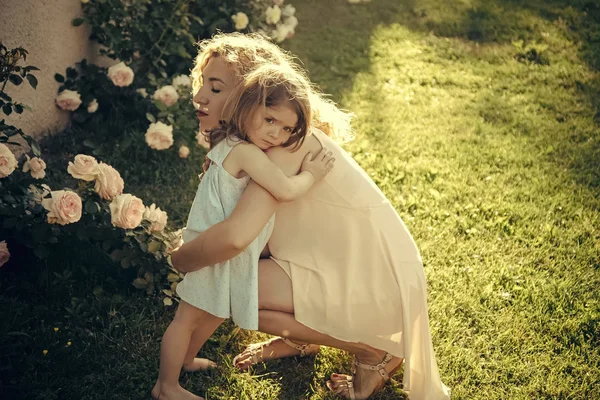 Anya cuddling lánya, a zöld fű, napsütéses nyári napon — Stock Fotó