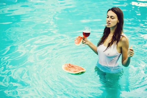 Meisje rokend met watermeloen en wijn in zwembad — Stockfoto