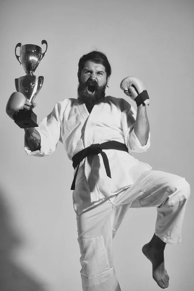 Bearded happy karate man in kimono, boxing gloves, champion cup — Stock Photo, Image